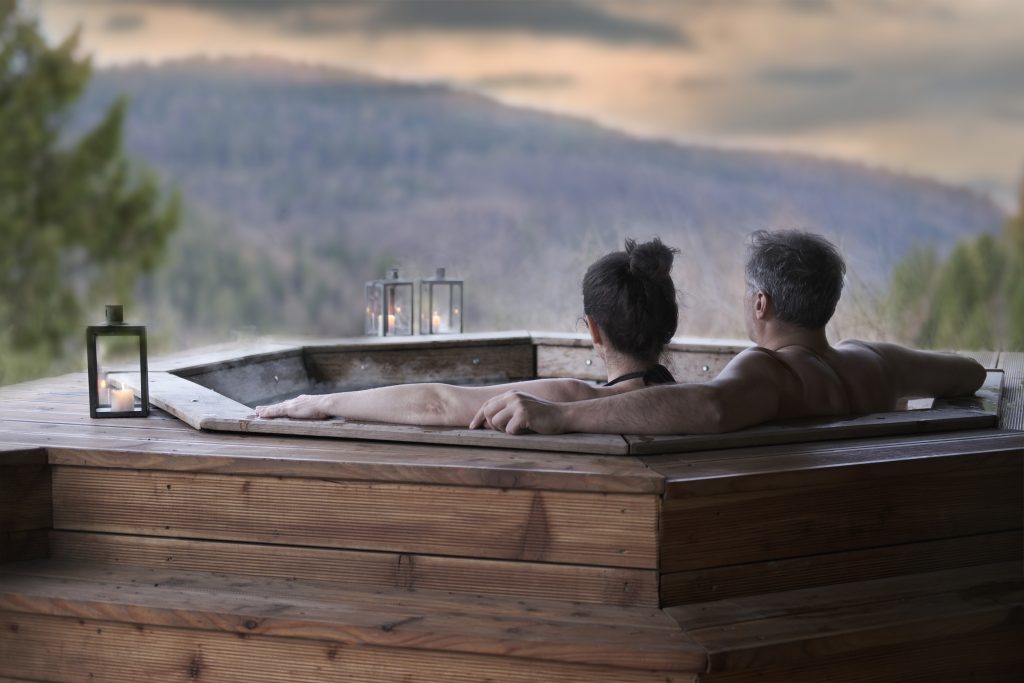 The young couple in an open-air bath with a view of the mountains.