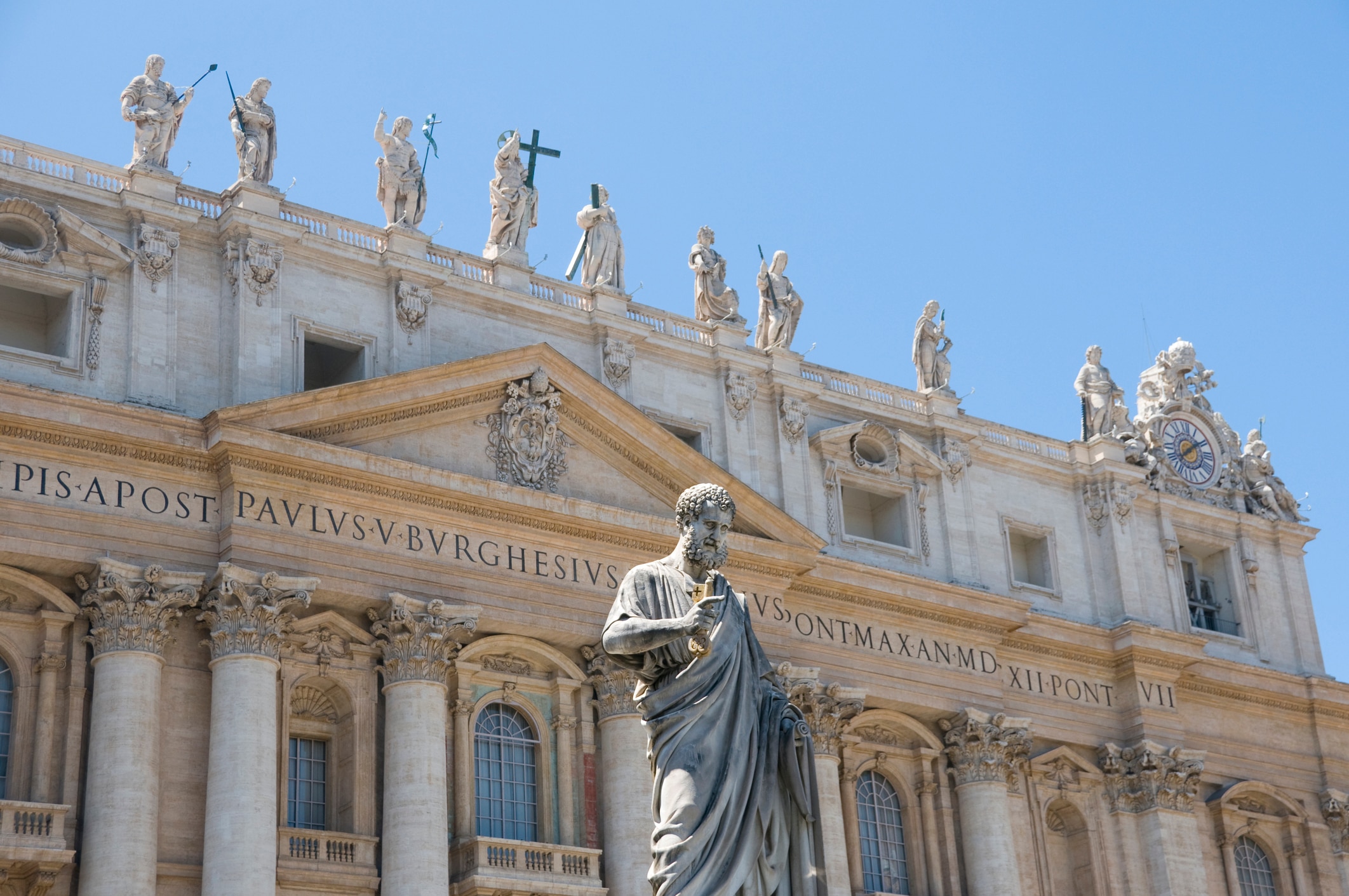 The beautiful facade of the Basilica of St Peter in Vatican City, Rome.Crowned by statues of Jesus Christ and the saints. In the foreground is the noble statue of St Peter,holding the ""keys of the Kingdom"" given him by Christ as a symbol of his spiritual power as prince of the Apostles and the ""rock"" upon whom Christ founded His Church.