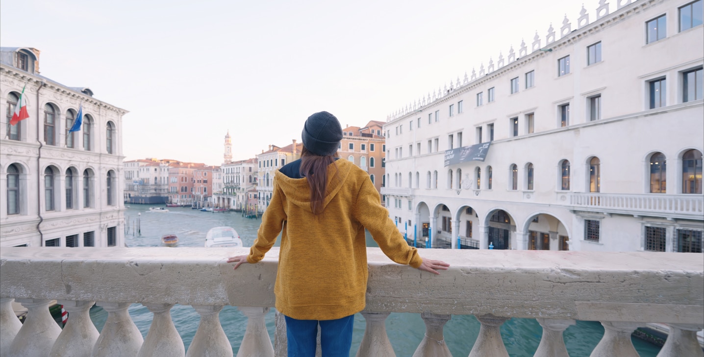 Tourist woman enjoying view of Venice canal on bridge,Italy at morning.Enjoying Life Moments.