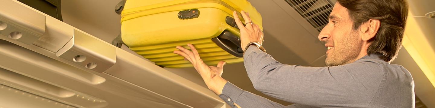 Passenger placing luggage in the overhead locker

