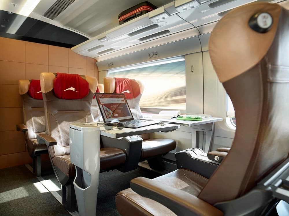 Interior of an Italo train with soft seats and a PC with on-board entertainment on the screen